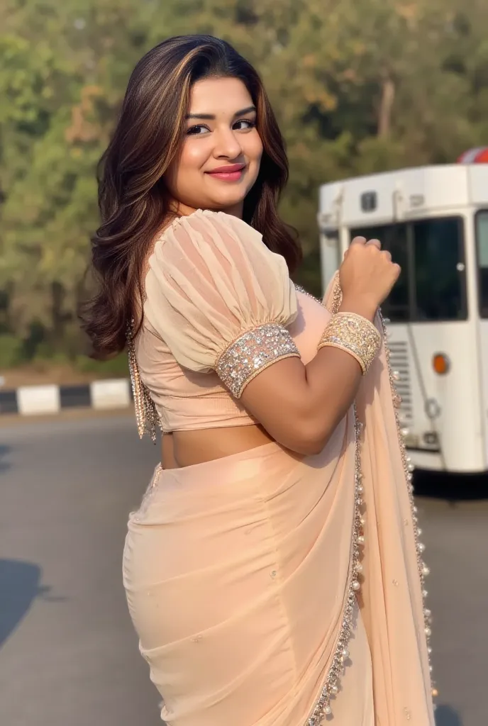 A young woman, likely in her twenties, is shown from the mid-thigh up.  She is of South Asian ethnicity, with long, dark hair.  She is wearing a light peach-colored saree with intricate, detailed silver and pearl embellishments on the shoulder-length sleev...