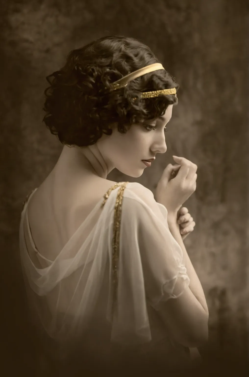 arafed woman in a white dress with a gold headband, has dark short curly hair with gold embellishments, golden 1920s, elegant lady, She is facing slightly to the right and downward with a thoughtful expression, The woman is draped in a white sheer fabric t...