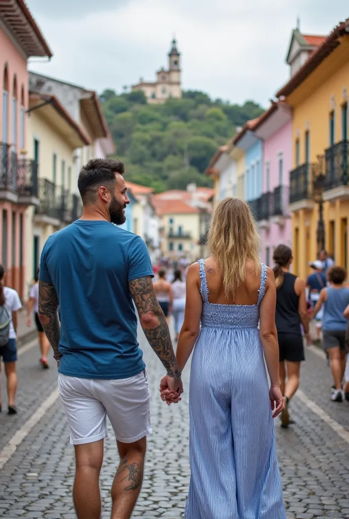 The image shows a couple on a cobblestone street in a historic area, with several people walking. In the foreground, there are two people with their backs, holding hands. Tanned white skin man, completely tattooed, shaved black hair, happy, brown eyes, sho...