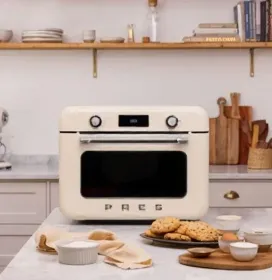 an warm light minimalist kitchen medium shot with an portable oven standing at the top of minimalist table and surrounded by various bake and roasted food
