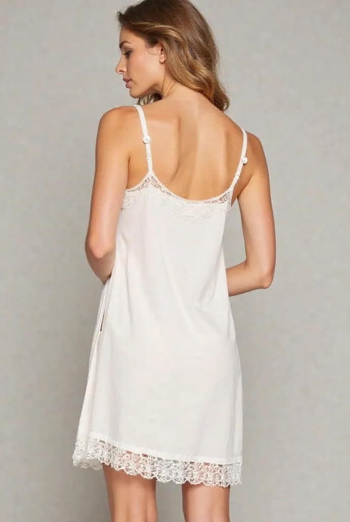 The picture shows a woman wearing a short white silk nightgown. The dress has thin straps and has a side opening along the side.  The dress has white lace along the edges and the side opening.  The dress looks elegant and soft.