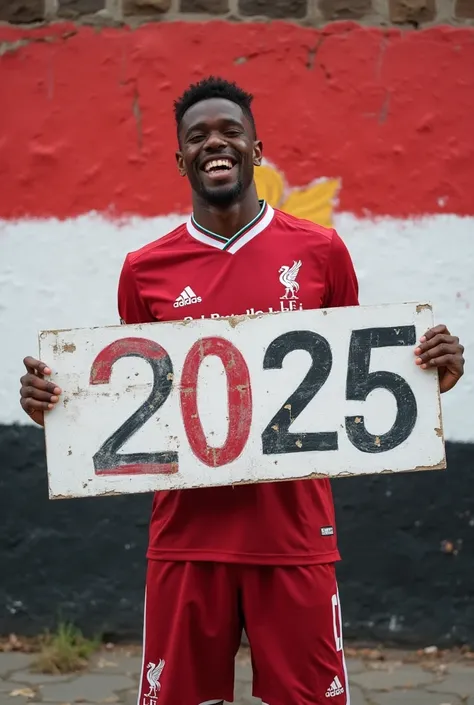  Liverpool player Dike is enthusiastically holding a banner with a bold three-dimensional name " Emad Alshayeb 2025 " Behind it is a wall painted in the colors of the Egyptian flag 