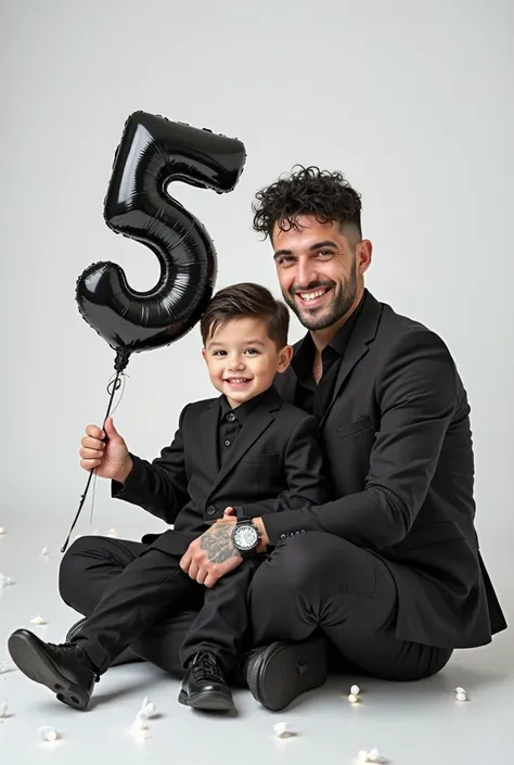 A Young father and  son , They are white with short black curly wet hair, smile. Both are wearing modern tailored black suits. They Sitting on the floor holding black balloons that form the number '5'. White LED lights around the floor. The adult brother 2...