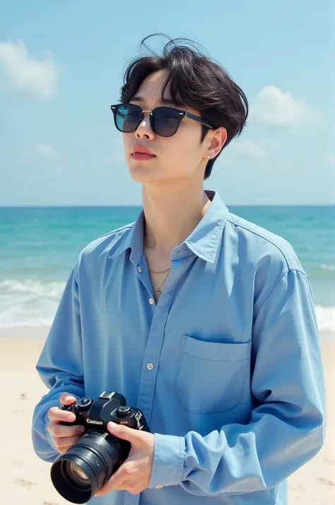 MEMBER OF THE SOUTH KOREAN GROUP BTS PARK JIMIN ON IPANEMA BEACH WEARING A BLUE DRESS SHIRT, SUNGLASSES AND HOLDING A CAMERA 