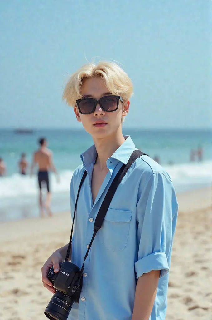 MEMBER OF THE SOUTH KOREAN GROUP BTS PARK JIMIN ON IPANEMA BEACH WEARING A BLUE DRESS SHIRT, DARK GLASSES AND HOLDING A CAMERA AND BLOND HAIR