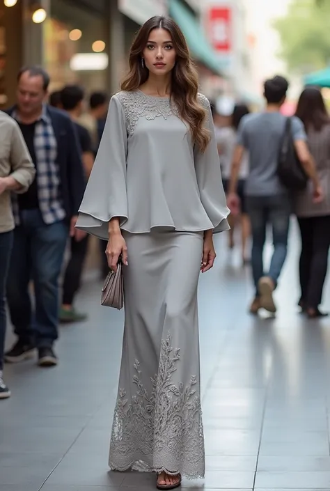 A glamorous and sophisticated woman, wearing a modern grey kurung in soft and elegant grey. The top features a loose and flowing silhouette with a round neckline. The wide sleeves are decorated with intricate lace embellishments, adding a soft and feminine...