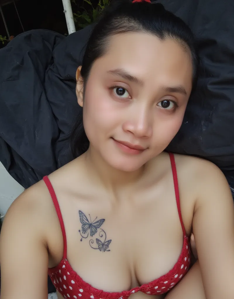 Amateur shot a pov of a instagram selfie. A breathtaking Indonesian woman in red polkadot bikini, approximately 26 years old, with long black hair neatly tied into a high ponytail. She has a soft smile on her red lips, a fit and toned physical appearance w...