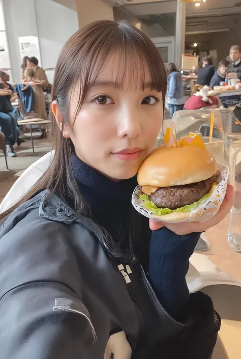 A young woman with long dark hair styled in two braids, wearing a black sports jacket with white stripes on the sleeves, holding a hamburger wrapped in white paper with a yellow logo. She is sitting in a casual indoor setting with a blurred background, pos...