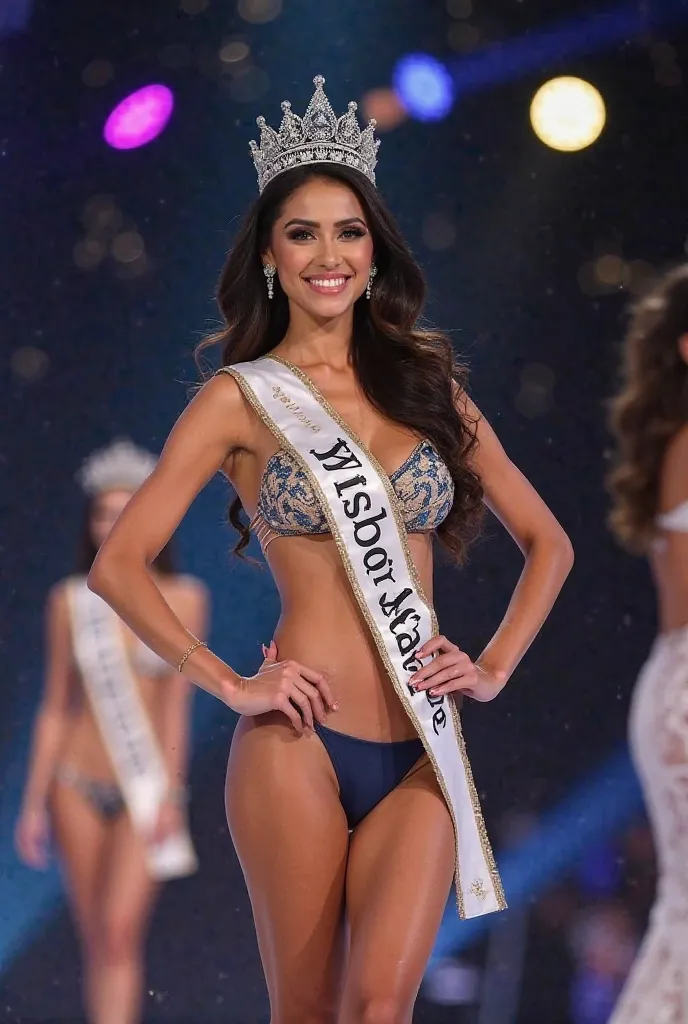 A beautiful Cambodia-European beauty queen wearing a Miss Wisdom Singapore sash and a crown in a swimsuit with big breasts is posing gracefully on a stage with lights and behind the scenes, with a nearby beauty queen blurred.