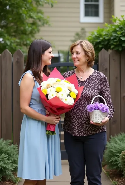 Full outdoor shot of two women. 


The woman on the left, who is younger, is wearing a light-blue, knee-length, A-line dress. She has dark brown hair, and she is holding a large bouquet of white, yellow, and light peach colored flowers wrapped in red and p...