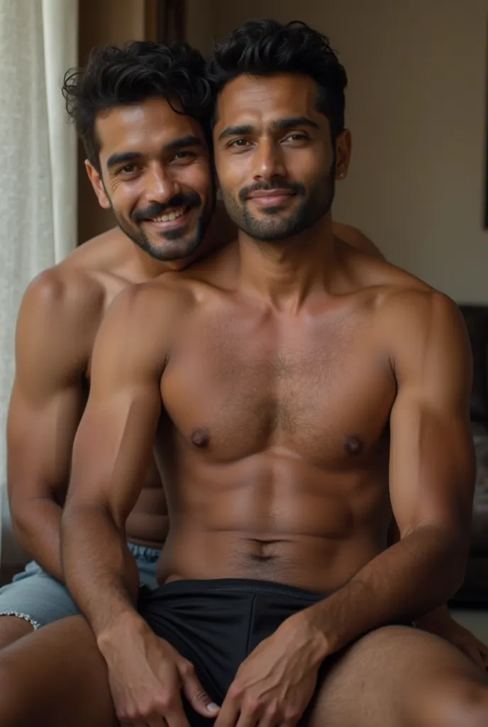 An Indian man, sitting on his friend's lap, both wear black underpants.