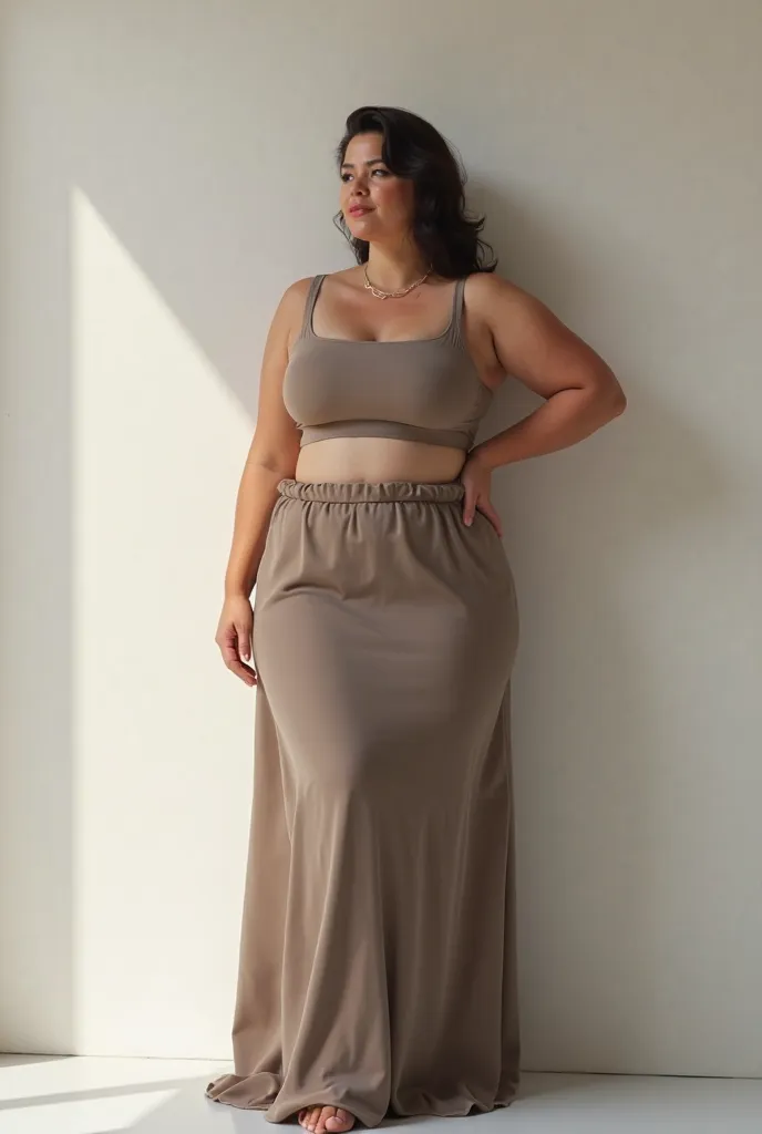 Plus-size woman with her back to the wall, wearing a long straight skirt, cropped with straps and square neckline