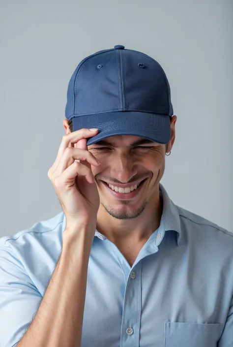 A man wearing a simple blue cap and a shirt, smiling and tilting his head slightly downwards, while holding the cap brim with one hand. The background is simple and light gray . Your expression is relaxed and cheerful, and his face is partially obscured b...