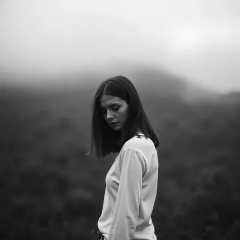 "Fine art editorial portrait of a young woman with auburn layered hair and fair skin, standing in profile against a blurred, fog-covered landscape of green hills. She wears a plain, ivory long-sleeved shirt. The lighting is soft and diffused, evoking a moo...