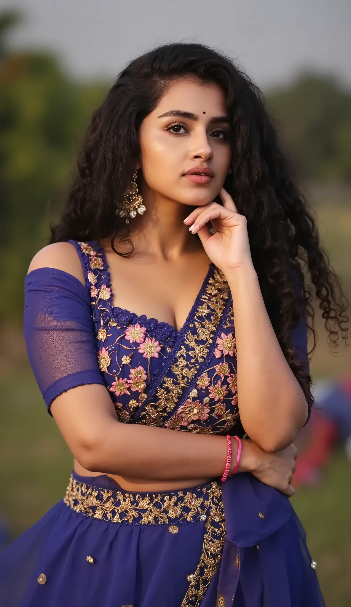 Female outdoor wearing dressed in traditional Indian attire. The outfit consists of a blue blouse with golden patterns and a matching blue skirt with