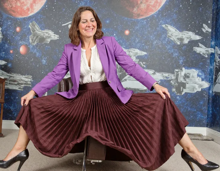  A stunning portrait captures my mother's mature beauty as she sits confidently on top of her desk, daringly spreading her legs amidst a vibrant space station backdrop featuring galaxies and spaceships. Her long pleated skirt flows around her, juxtaposing ...