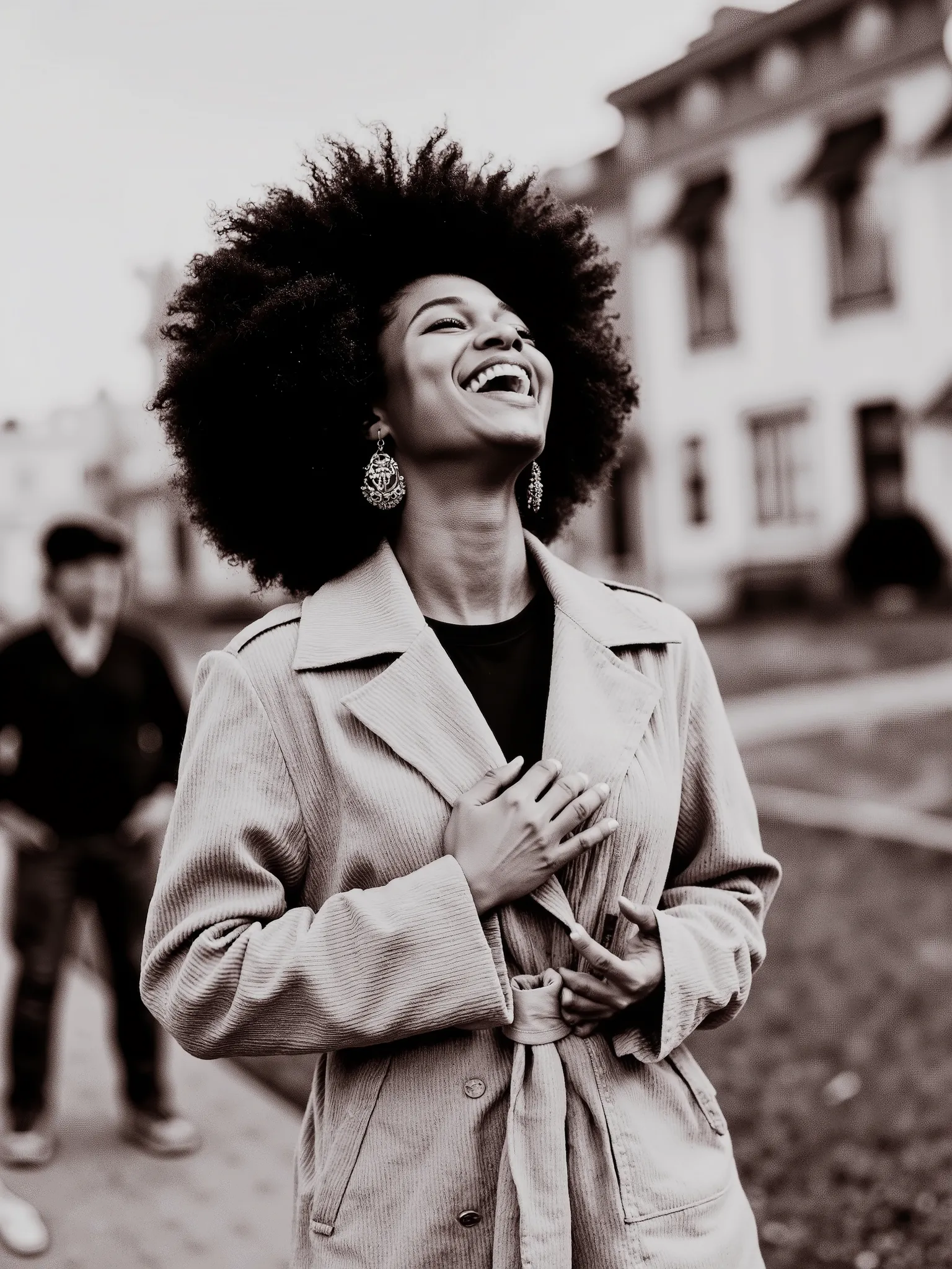 Ultra-realistic black and white photograph of a joyful woman laughing heartily in an outdoor urban neighborhood setting. She has a voluminous curly afro hairstyle and wears large, ornate chandelier earrings. Her expression is full of life and energy, mouth...