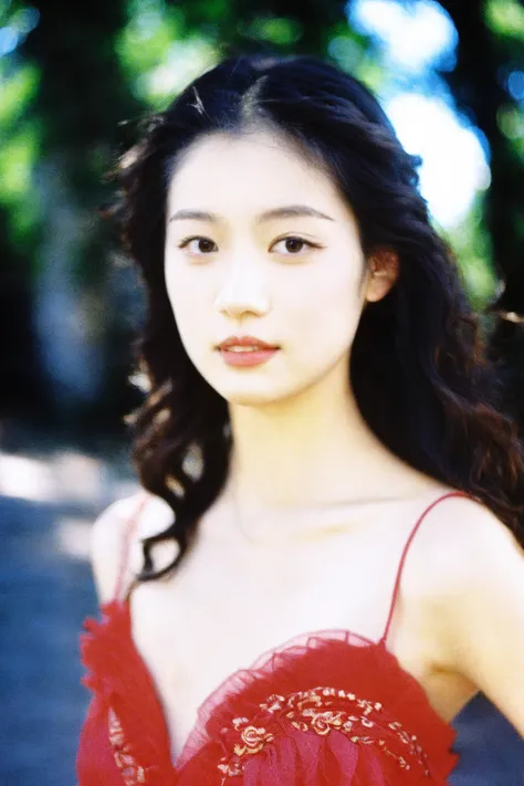 Film photography,Kodak 400 shooting,young woman,Asian ethnicity,red dress,outdoor portrait,natural light,long hair,wavy hair,hand on shoulder,looking at camera,soft focus background,bokeh effect,daytime,natural makeup,subtle smile,clear skin,sleeveless dre...