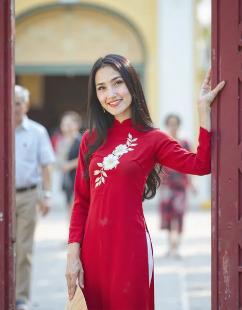 Vietnamese, aodaivnv5, The image is a portrait of a young woman wearing a traditional Vietnamese dress. She is standing in front of a red gate and is holding a bamboo fan in her left hand. The dress is red with white embroidery on the neckline and sleeves....