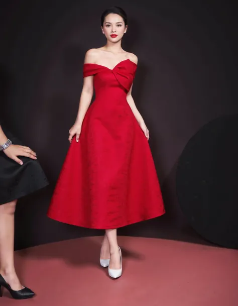 RC Hoang, Vietnamese, vaydo01, a young woman wearing a red knee-length dress. The dress has a sweetheart neckline with a bow detail at the waist. The skirt of the dress is full and flows down to the floor. The woman is wearing white high heels and has her ...