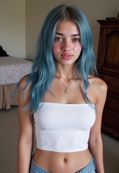 Amateur selfie of a young woman with long, straight blue hair. She is standing in a bedroom with a bed and a dresser in the background. The woman is wearing a white strapless crop top and light blue jeans. She has a necklace with a star pendant around her ...