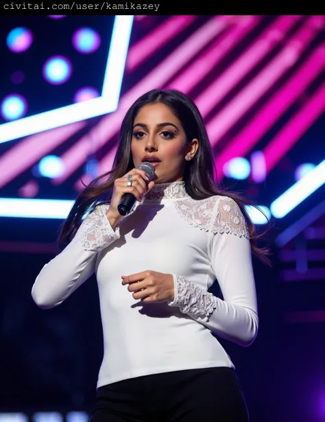 This photograph captures banita_sandhu singing into a microphone on stage, set against a vibrant, multicolored backdrop. She has light skin and long, wavy brown hair that falls over her shoulders. Her attire is elegant and sophisticated, featuring a long-s...