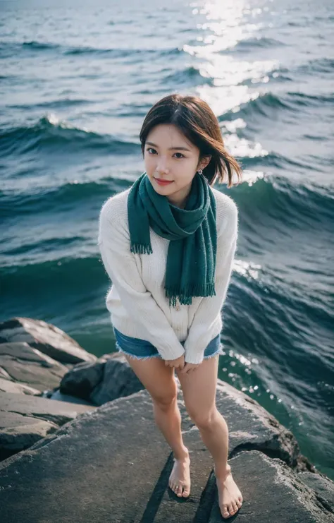 a woman standing on a rock near the ocean wearing a scarf