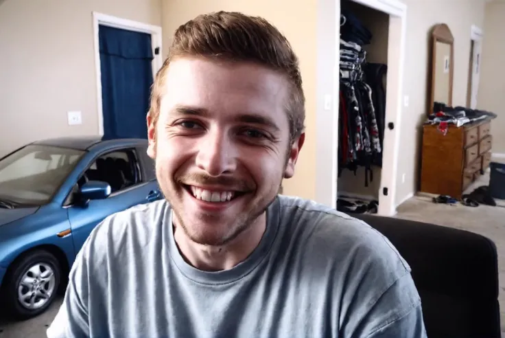 smiling man in a room with a car and a blue car