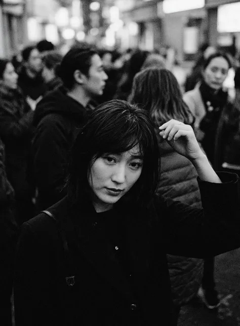 (A black and white photograph:1.1),shot from above,empty Tokyo city street late at night, an Asian woman walking through crowd, looking to viewer, short black hair, wearing a black YSL suit jacket, reflecting the cold, artificial light of the city. The atm...