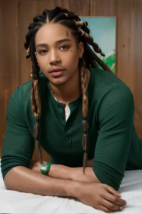 man laying head over crossed arms and legs spread open, light brown dreadlocks, balbo shaving, wearing emerald green henley shir...