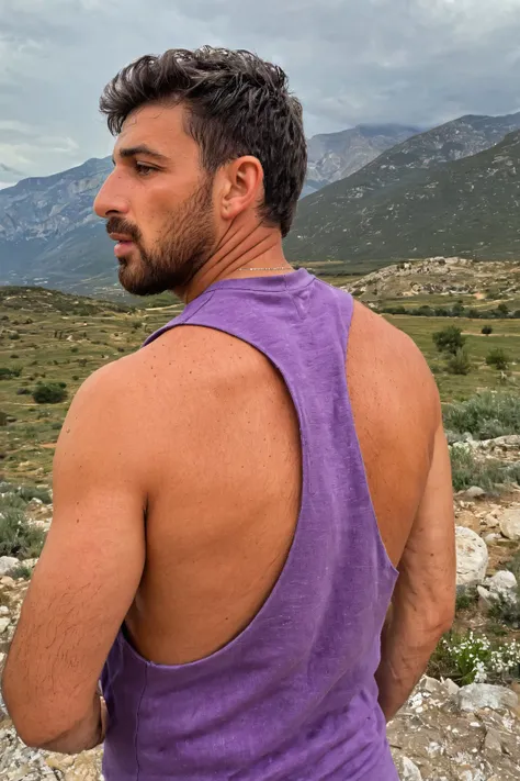 arafed man in a purple tank top standing on a rocky hill