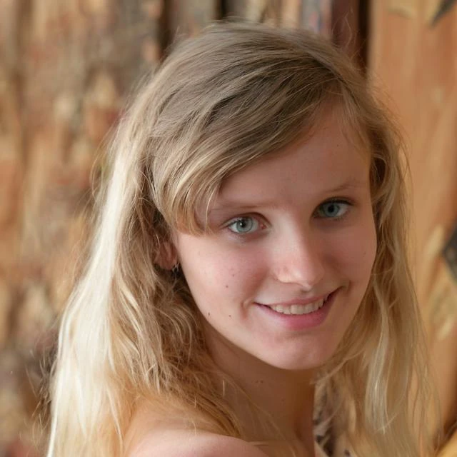 blond haired girl with blue eyes and a smile holding a banana