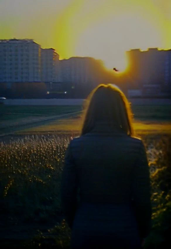 araffe woman standing in a field looking at the sun