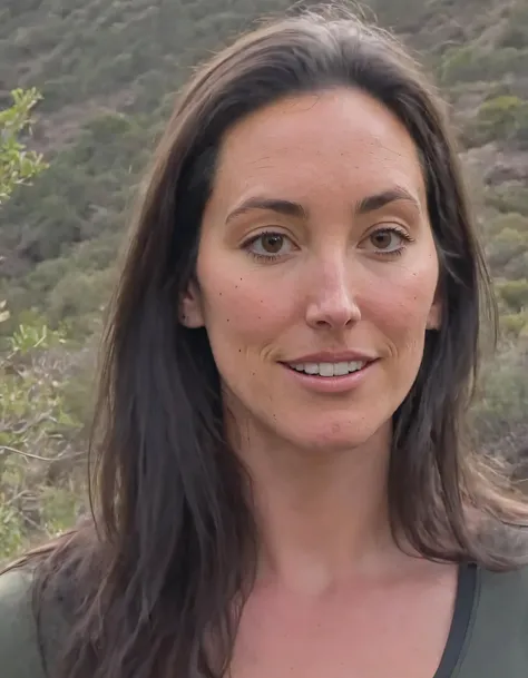 arafed woman with long hair and a green shirt standing in front of a mountain