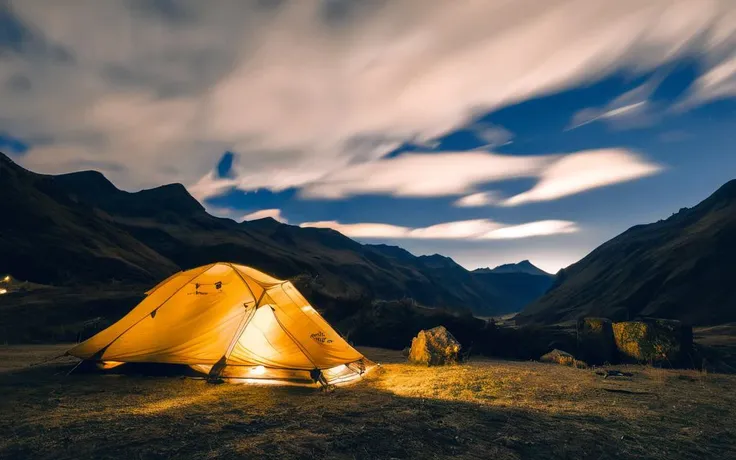 arafed tent in the middle of a field with mountains in the background