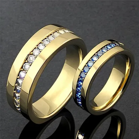 two gold wedding rings with blue and white diamonds on a black surface