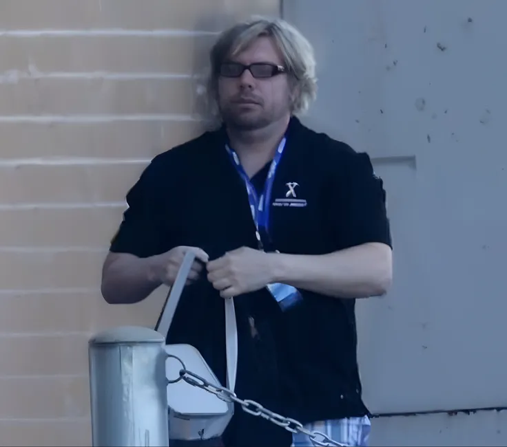 sharp focus photo of a man standing next to a metal poll with a chain connected to it, hig res, high resolution, clear