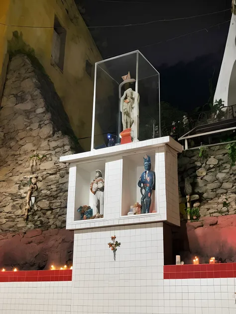 There are two statues of people in a glass box on one wall, Porque Sepulto, exibido em um altar, photo taken at night, bem decorado, Directed by: Daniel Lieske, artista desconhecido, altar sacrificial, Directed by: Matteo Pérez, Sanctuary, taken in the nig...