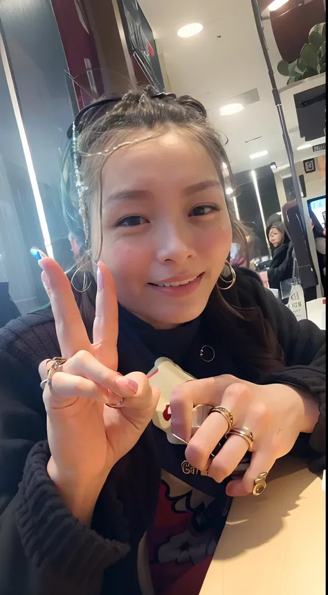 smiling woman sitting at a table with a cell phone in her hand, with index finger, captured on iphone, kiyoko suzuki, with fingers, wearing two metallic rings, junko enoshima, in tokio, ann takamaki, giving the middle finger, chiho ashima, taken in the ear...