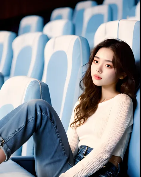 Cinematic Photo of a beautiful korean fashion model, 20 years old, perfect body, perfect skin, loose long hair, micro curls, tight jeans, white crop top, knit long sleeve, sitting in movie theater