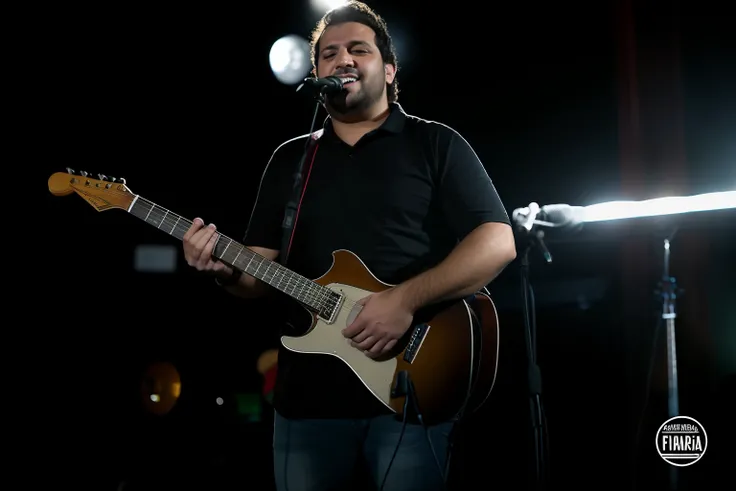 Arafed Man Playing a Guitar in a Dark Room, playing guitar on stage, Ed OBrien (acoustic guitar), Alex Miranda, Alex Flores, Miguel Vicente, Mike Stoklasa, Maurício Franchina, acoustic guitarrista, Foto de um ensaio promocional, danilo torres, joe alves, J...