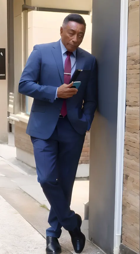 Homem com 30 anos, pele morena, cabelo curtinho preto vestindo terno azul e gravata roxa, Using a cell phone in his hands leaning against a wall.