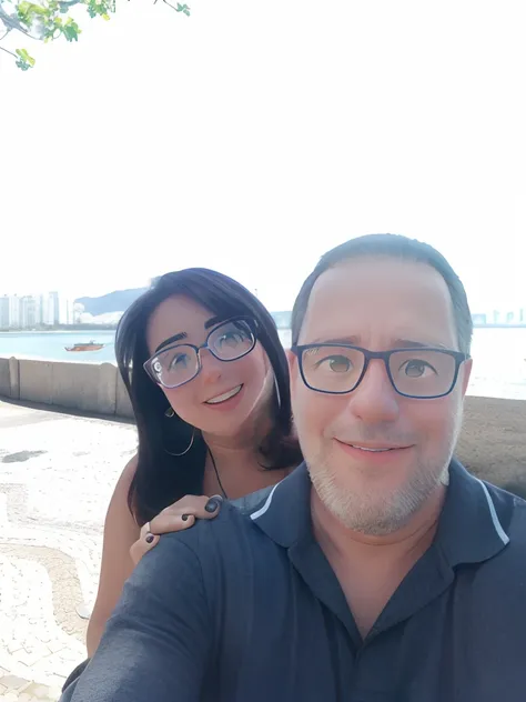 Theyre taking a selfie of themselves in front of the water, casal feliz