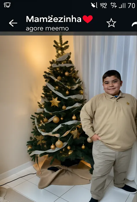 A boy next to a Christmas tree with his hand in his pocket.