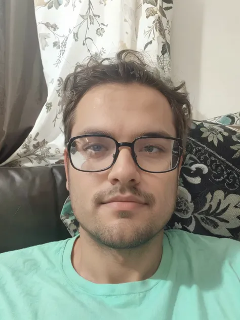 Man in black frame glasses, cabelo castanho, calvo, blusa verde, barba feita recentemente, olhos castanhos, blusa verde, sitting on brown sofa, cabelo despenteado