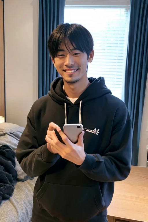 Smiling handsome Japanese man absorbed in his smartphone,inside in room,wearing hoodies,I have a smartphone