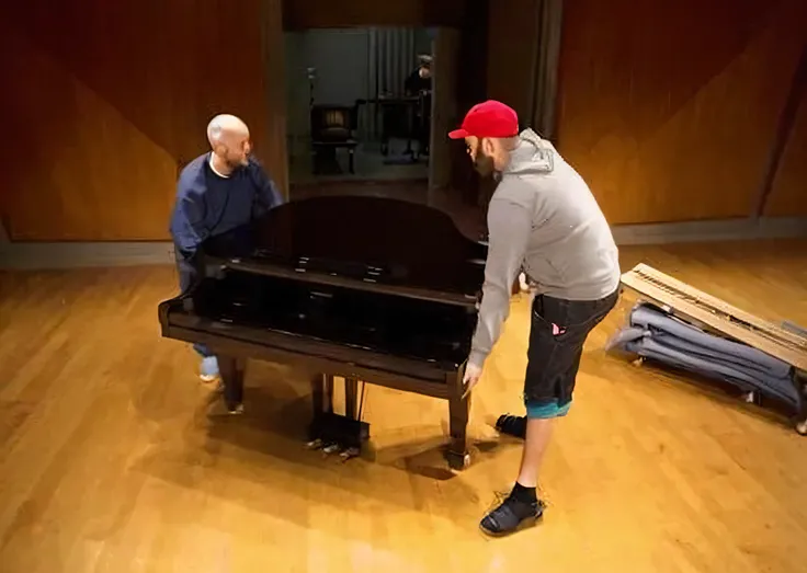 They were moving the piano together in a room with wooden floors, Next to the piano, They want to move the piano