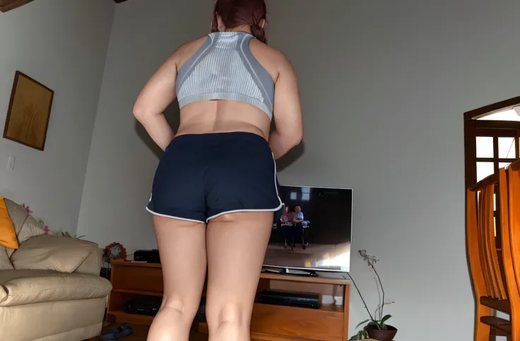 There is a woman standing in a living room with a TV, sport bra and dark blue shorts, sport bra and shorts, seen from back, Bermuda, tiro longo das costas, view of the back, tiro pelas costas, Backview, tiro longo de costas, Back view!!, from the back, boo...