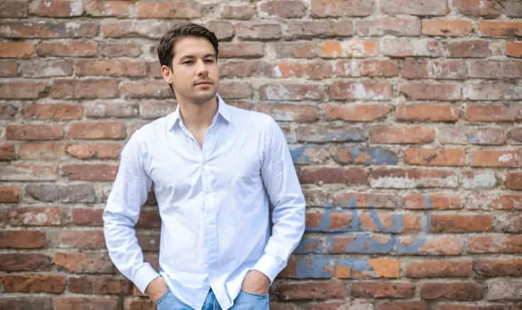 man leaning against brick wall