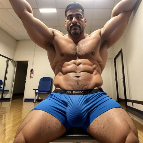 40 year old physical education teacher, en boxers, with a very large and long bulge in the crotch, sentado en una silla, front facing camera, guapo latino.